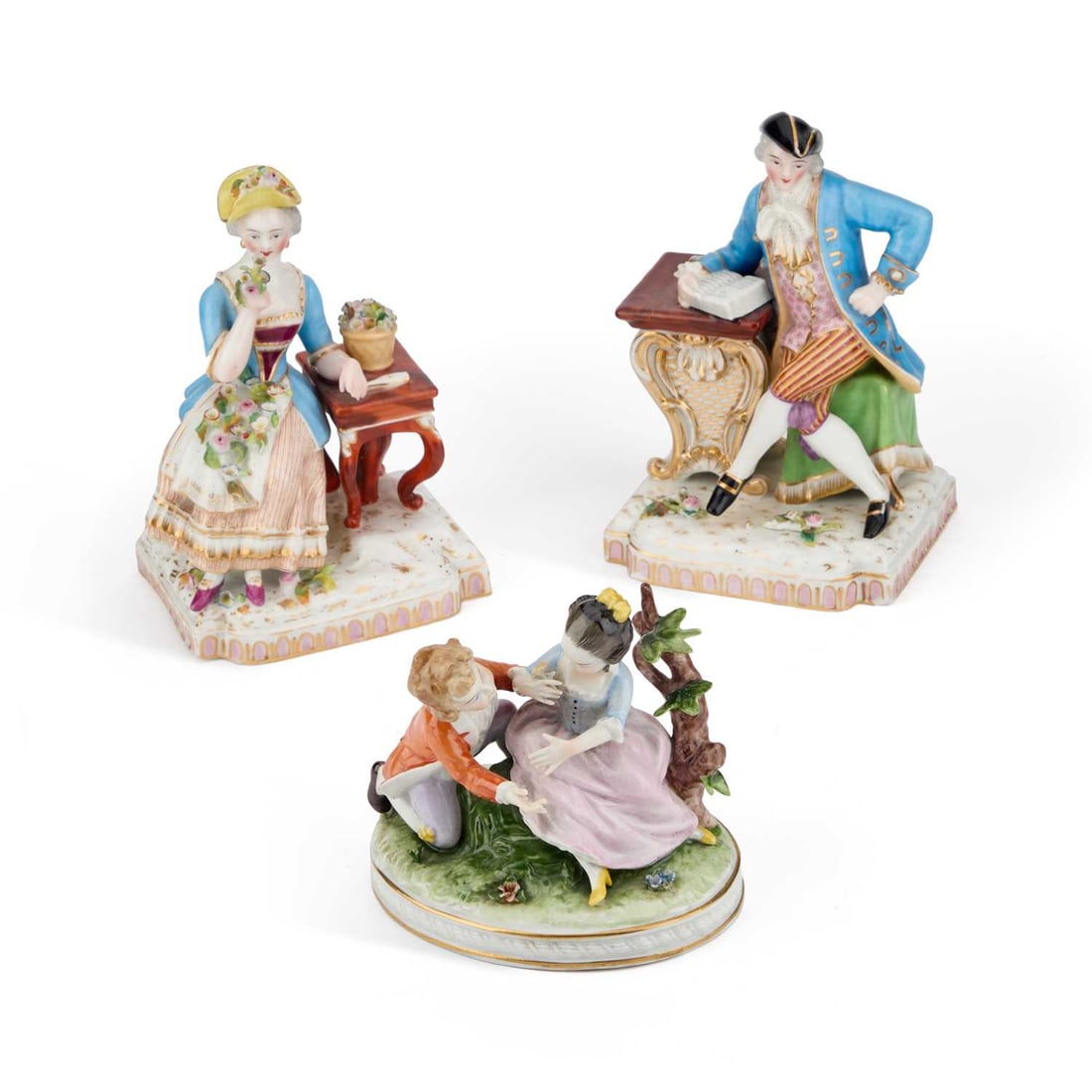A PAIR OF JACOB PETIT PORCELAIN FIGURES, 19TH CENTURY: A PAIR OF JACOB PETIT PORCELAIN FIGURES, 19TH CENTURY each modelled as a lady and gentleman in 18th Century dress sitting at a desk, underglaze blue JP marks; together with a Naples porcelain figure g