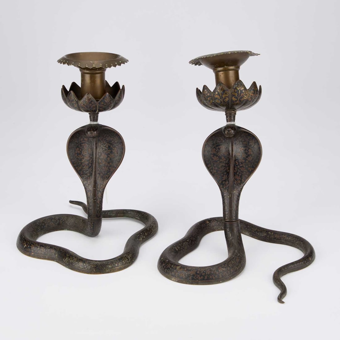 A PAIR OF DAMASCENED COBRA CANDLESTICKS: A PAIR OF DAMASCENED COBRA CANDLESTICKS 22.5cm high