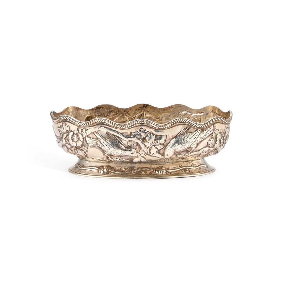 A VICTORIAN SILVER TABLE DISH: A VICTORIAN SILVER TABLE DISH by Charles Stuart Harris, London 1882, oval, chased with birds perched on blossoming boughs. 15cm long, 5.3 troy ounces