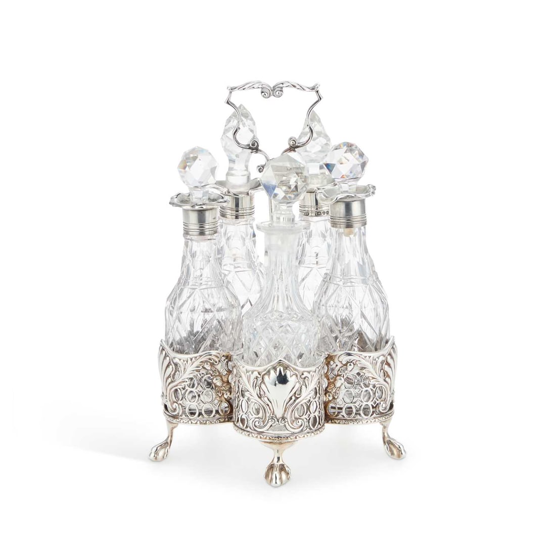 A VICTORIAN SILVER CRUET STAND: A VICTORIAN SILVER CRUET STAND by Charles Thomas Fox & George Fox, London 1852, the cinquefoil stand with pierced sides chased with shells and scrolls, fitted with five cut-glass bottles, four wit