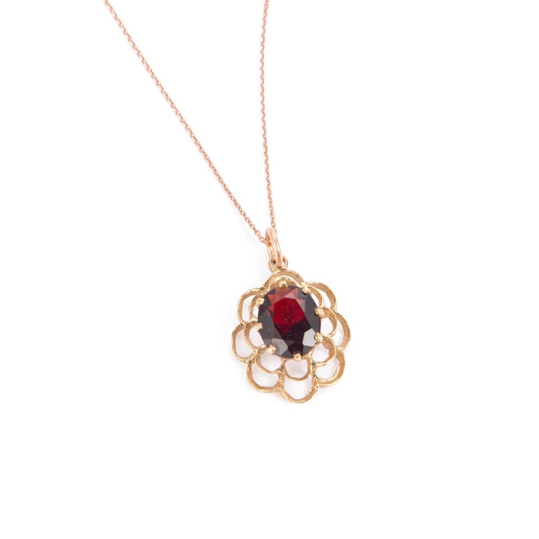A 9 CARAT GOLD GARNET PENDANT ON A ROSE GOLD CHAIN: A 9 CARAT GOLD GARNET PENDANT ON A ROSE GOLD CHAIN an oval-cut garnet within a fancy pierced frame, hallmarked London 1977. Pendant 2.5cm by 1.5cm, chain 45cm long, 2.4 grams gross Good condition