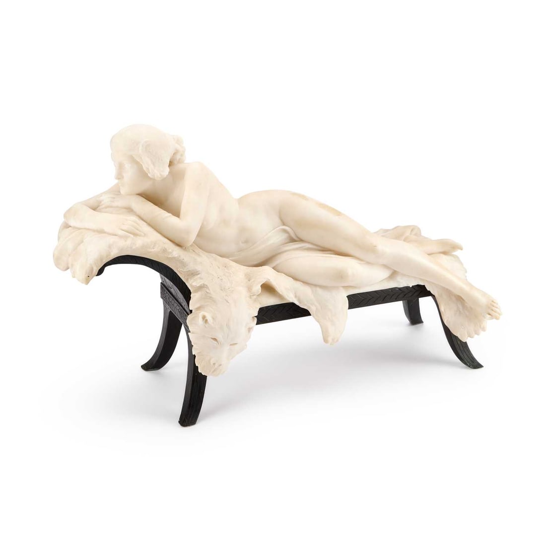 GIUSEPPE GAMBOGI (ITALIAN 1862-1938), A WHITE MARBLE CARVING OF A RECLINING FEMALE NUDE: GIUSEPPE GAMBOGI (ITALIAN 1862-1938), A WHITE MARBLE CARVING OF A RECLINING FEMALE NUDE the nude reclining on a lion skin rug on a bronze chaise lounge base, signed. 43cm high, 65cm wide, 25cm deep