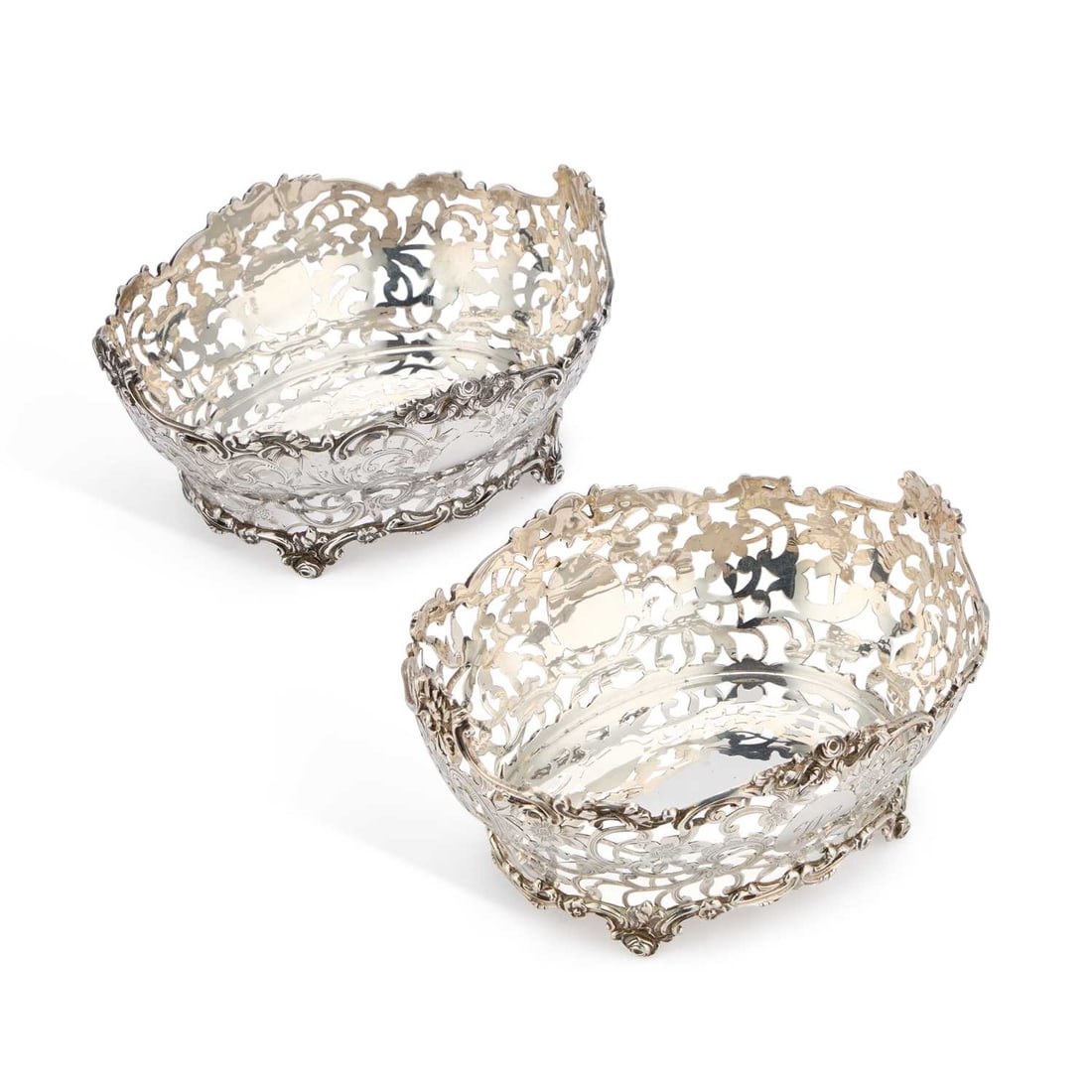A PAIR OF VICTORIAN SILVER TABLE BASKETS: A PAIR OF VICTORIAN SILVER TABLE BASKETS marks of Daniel & John Wellby (overstriking Charles Stuart Harris) and Charles Stuart Harris, London 1897, of shaped oval form, each with a beautifully det