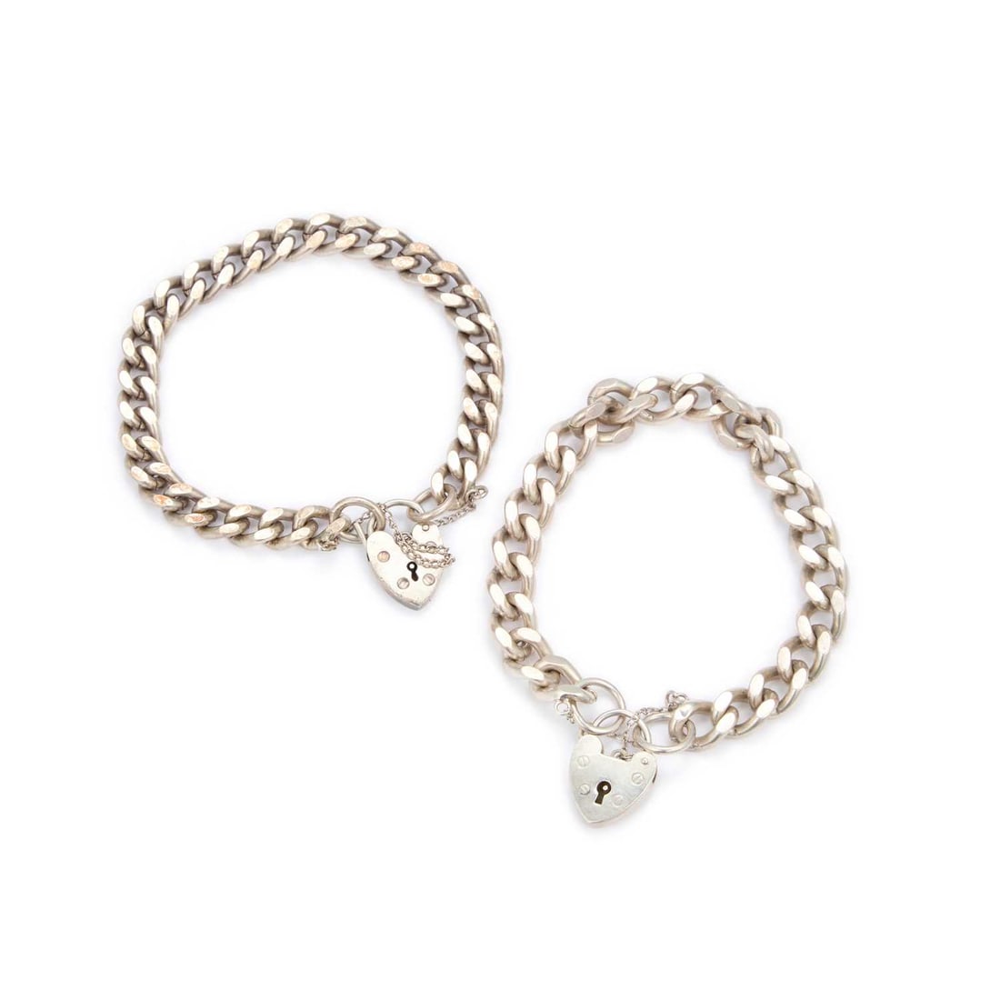 TWO SILVER CURB LINK BRACELETS WITH HEART PADLOCK CLASPS: TWO SILVER CURB LINK BRACELETS WITH HEART PADLOCK CLASPS both hallmarked. (2) 19cm long, 67 grams gross Good condition