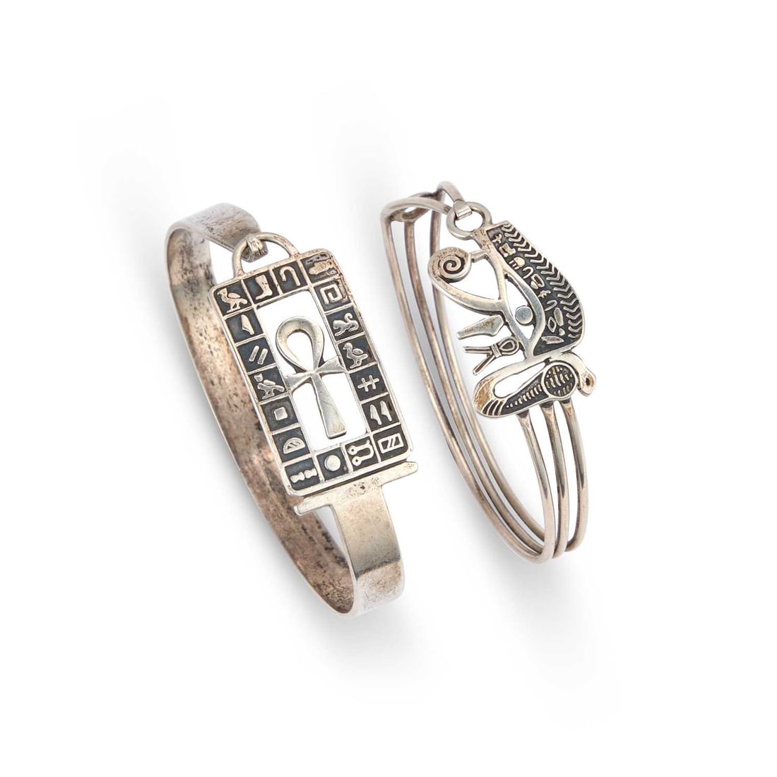 TWO EGYPTIAN REVIVAL BANGLES: TWO EGYPTIAN REVIVAL BANGLES including an Ankh example, and an Eye of Ra example, both with Egyptian assay marks. (2) 18.5cm inner circumference, 43 grams gross Ankh example bent out of shape.