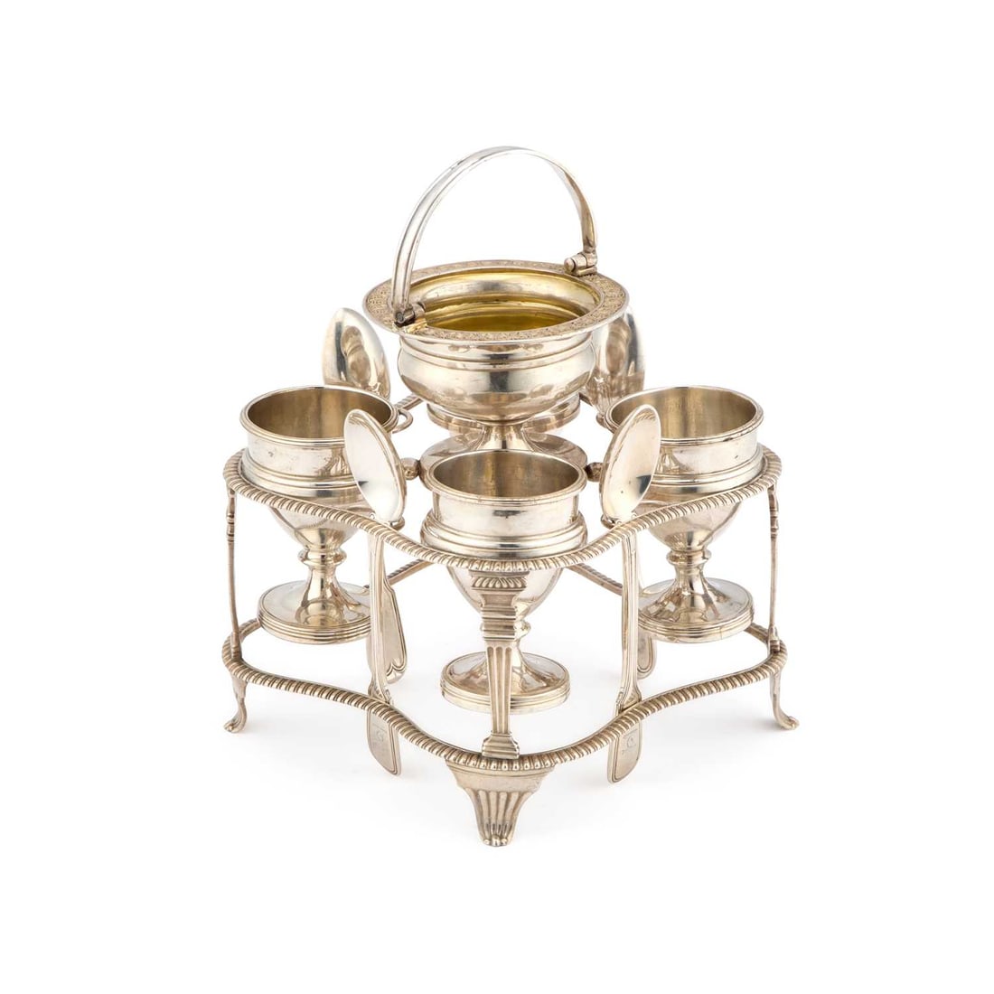 A GEORGE III SILVER EGG CRUET: A GEORGE III SILVER EGG CRUET by John Emes, London 1807, of shaped square form with gadrooned rims, the four egg cups with applied girdles sitting into circular reserves, surmounted by a swing-handle