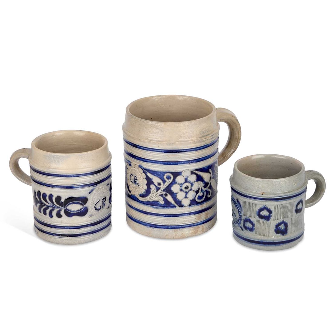 THREE WESTERWALD STONEWARE MUGS CIRCA 1800: THREE WESTERWALD STONEWARE MUGS CIRCA 1800 each decorated in blue with GR boss, foliage and other motifs. (3) Largest 17.5cm high