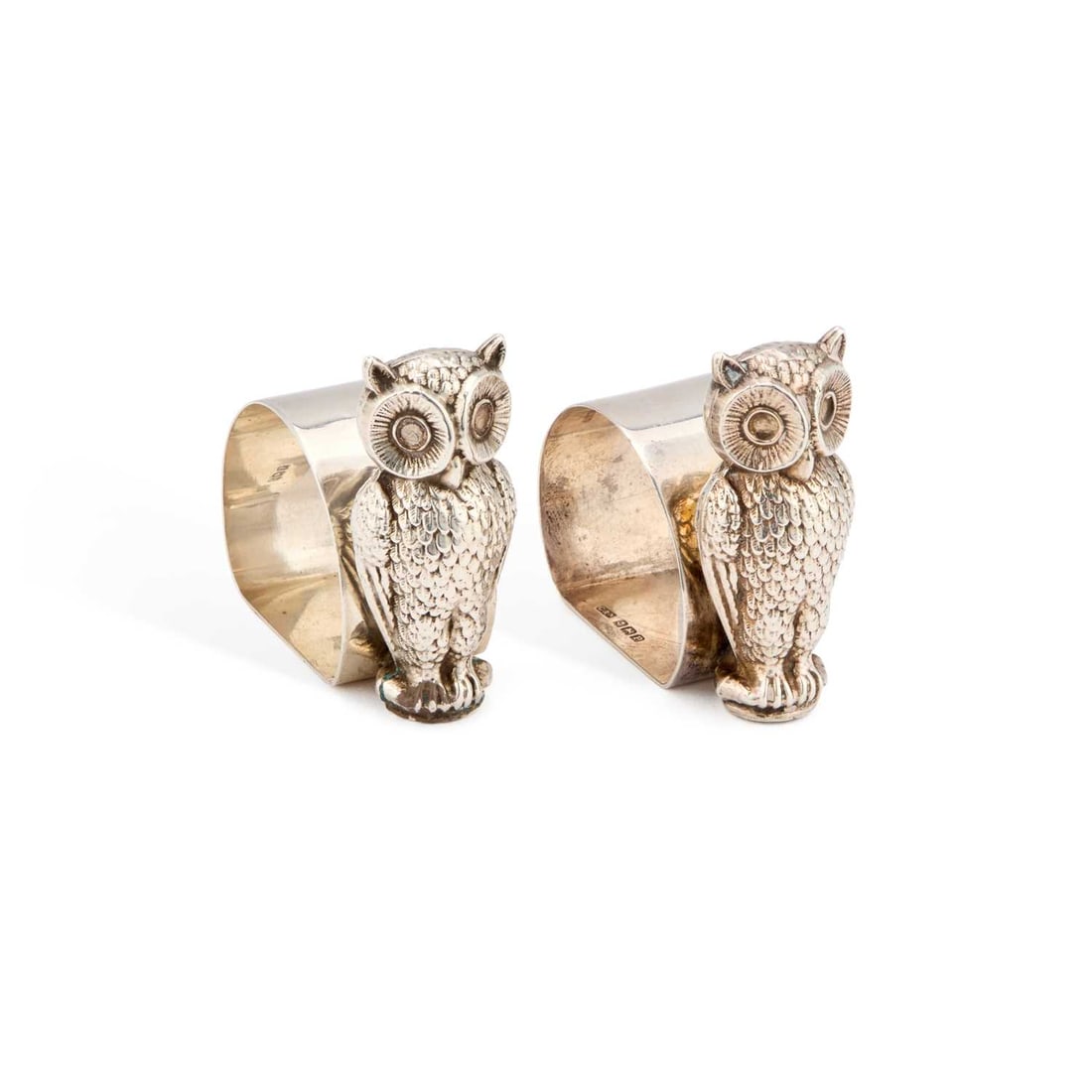 A PAIR OF GEORGE V SILVER NOVELTY NAPKIN RINGS: A PAIR OF GEORGE V SILVER NOVELTY NAPKIN RINGS by Crisford & Norris Ltd, Birmingham 1914, each circular ring with a flat base, supported by a double-sided owl. (2) 5.7cm high, 2 troy ounces gross