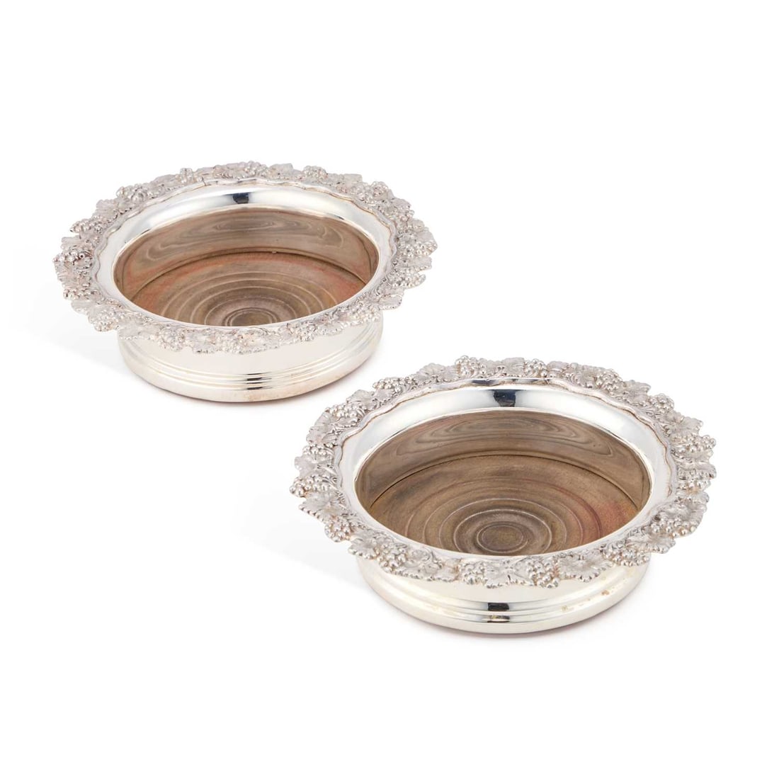 A PAIR OF OLD SHEFFIELD PLATE WINE COASTERS CIRCA 1820: A PAIR OF OLD SHEFFIELD PLATE WINE COASTERS CIRCA 1820 each circular coaster with a grape and vine pattern rim, turned wooden bases. (2) 17.5cm diameter