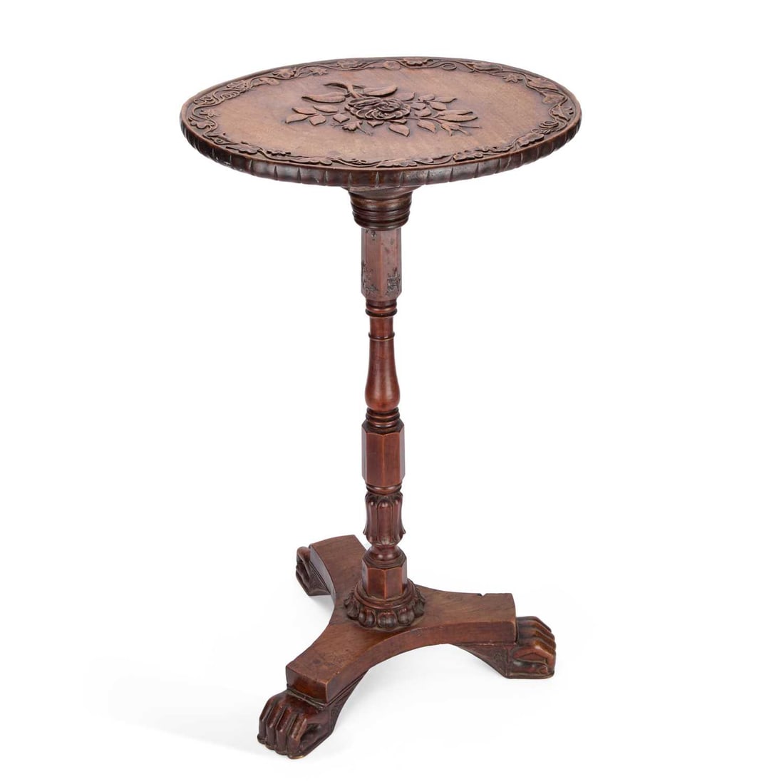 A YEW WOOD AND MAHOGANY TILT-TOP TABLE: A YEW WOOD AND MAHOGANY TILT-TOP TABLE the oval mahogany top carved with a flower spray within a vine border, raised on a yew wood base with a turned and faceted block stem issuing from a triform base