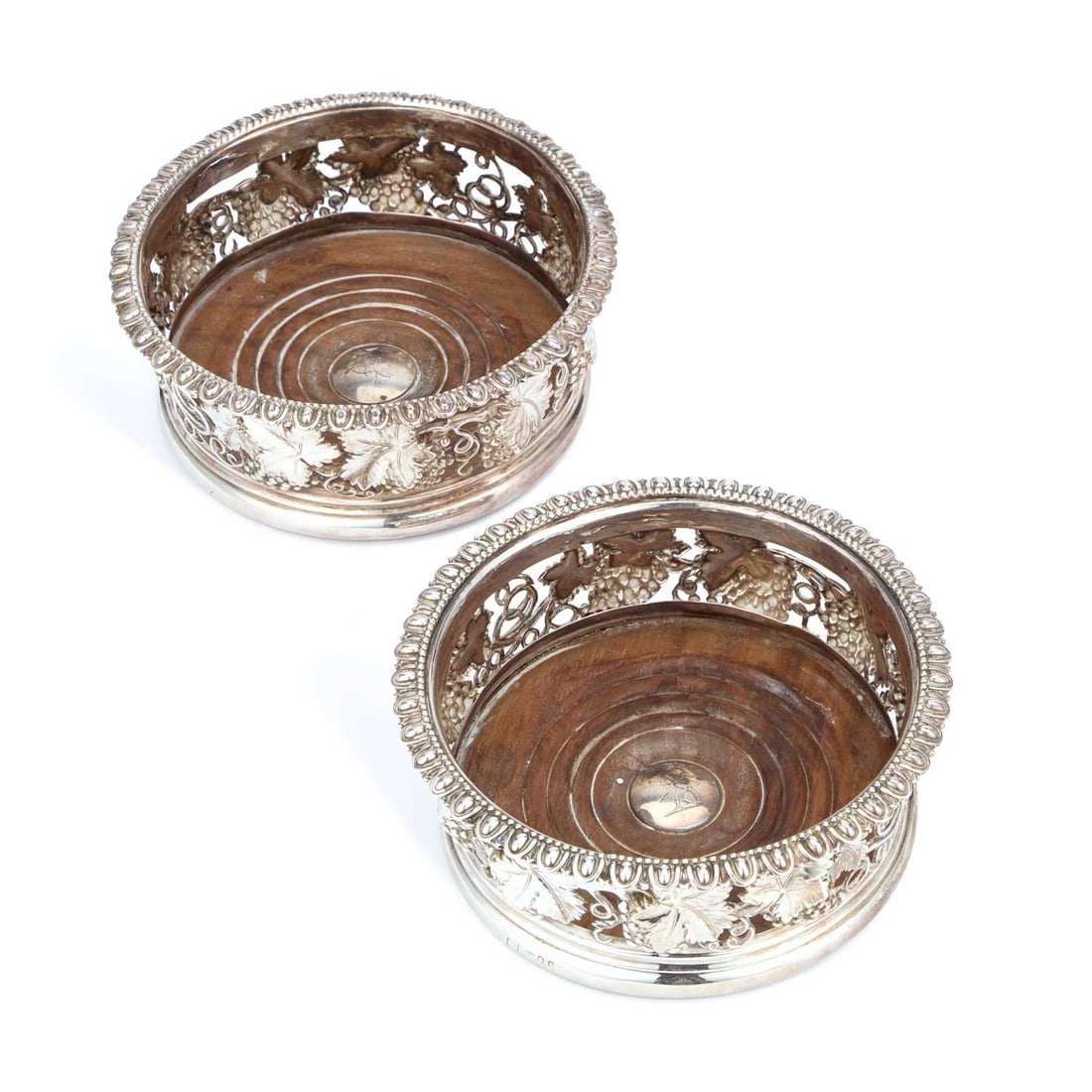 A PAIR OF GEORGE IV SILVER WINE COASTERS: A PAIR OF GEORGE IV SILVER WINE COASTERS Sheffield 1822, each of circular form with an egg-and-dart rim above pierced sides embossed with grapes and vine, the turned wooden bases centred by a roundel