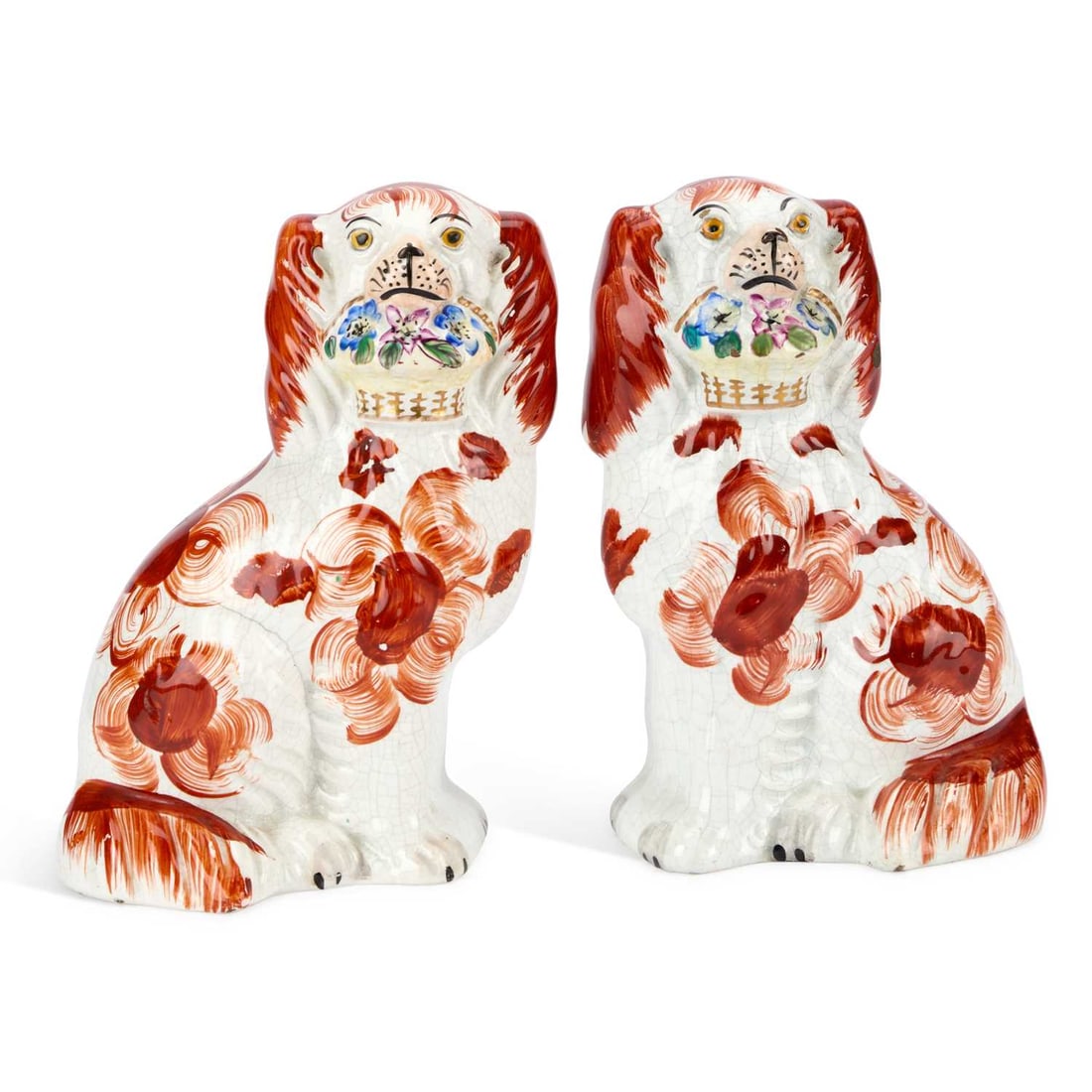A PAIR OF VICTORIAN STAFFORDSHIRE POTTERY MODELS OF FLOWER BASKET SPANIELS CIRCA 1850: A PAIR OF VICTORIAN STAFFORDSHIRE POTTERY MODELS OF FLOWER BASKET SPANIELS CIRCA 1850 each russet-patched, the seated dogs modelled holding a basket of flowers in their mouths. (2) 19cm high