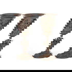 A PAIR OF LATE 19TH CENTURY CAST IRON VASES: A PAIR OF LATE 19TH CENTURY CAST IRON VASES each with a tapering bowl and everted rim clad with fruiting vines, raised on a stem within a foliate-form collar, the circular foot cast with stiff leaves.