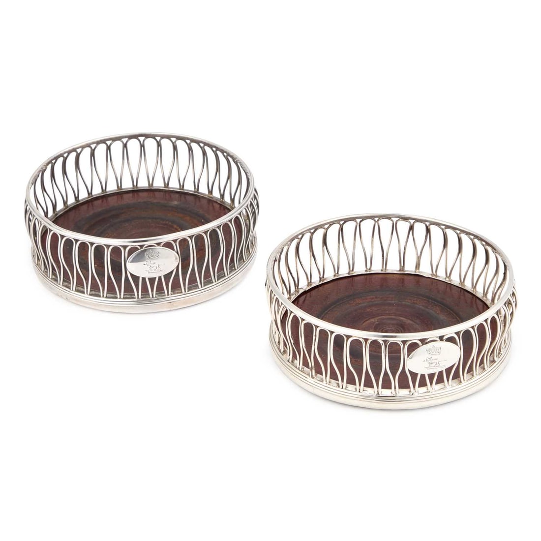A PAIR OF GEORGE III SILVER COASTERS: A PAIR OF GEORGE III SILVER COASTERS by Daniel Holy & Co., Sheffield 1790, of circular form with wirework sides and turned hardwood bases, each engraved with a crest. (2) 13cm diameter