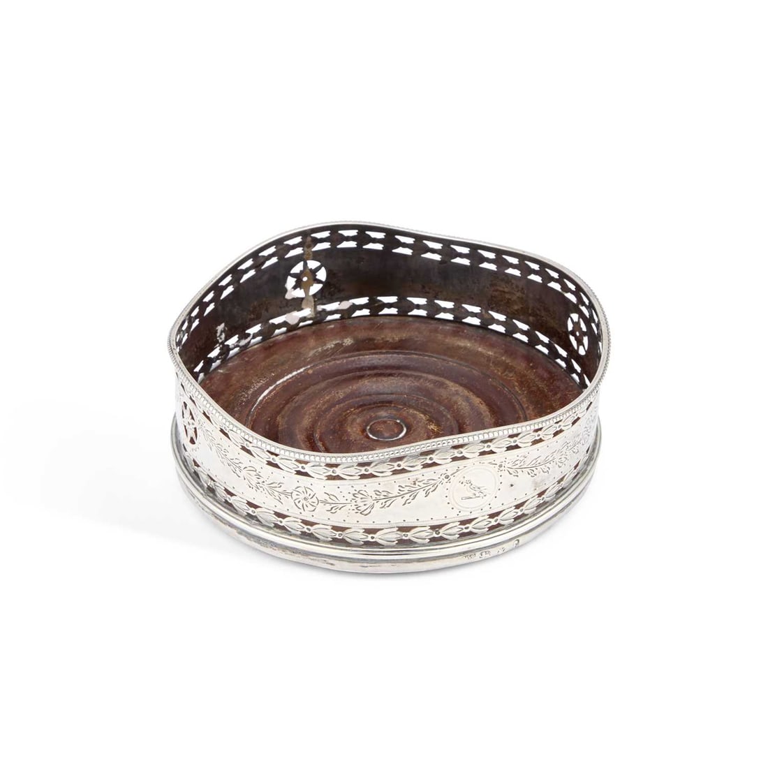 A GEORGE III SILVER WINE COASTER: A GEORGE III SILVER WINE COASTER by W.S, London 1781, of circular form, the beaded undulating rim above pierced sides engraved with foliate swags, with a turned mahogany base. 12.5cm diameter