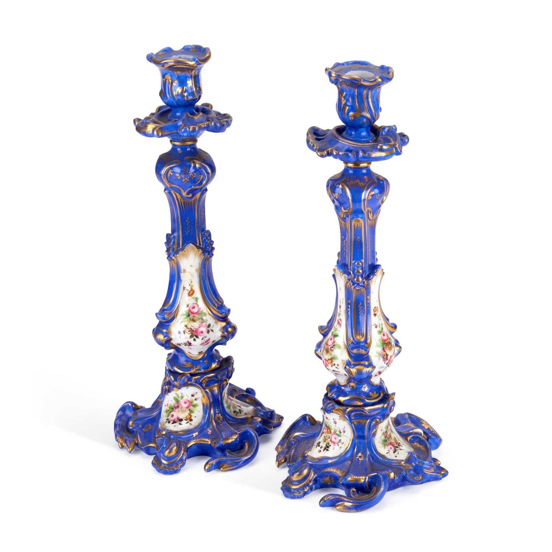 A PAIR OF 19TH CENTURY CONTINENTAL PORCELAIN CANDLESTICKS: A PAIR OF 19TH CENTURY CONTINENTAL PORCELAIN CANDLESTICKS each with cobalt blue and gilt scrolling Rococo moulded stems inset with floral reserves, on pierced scrolled bases. (2) 32cm high