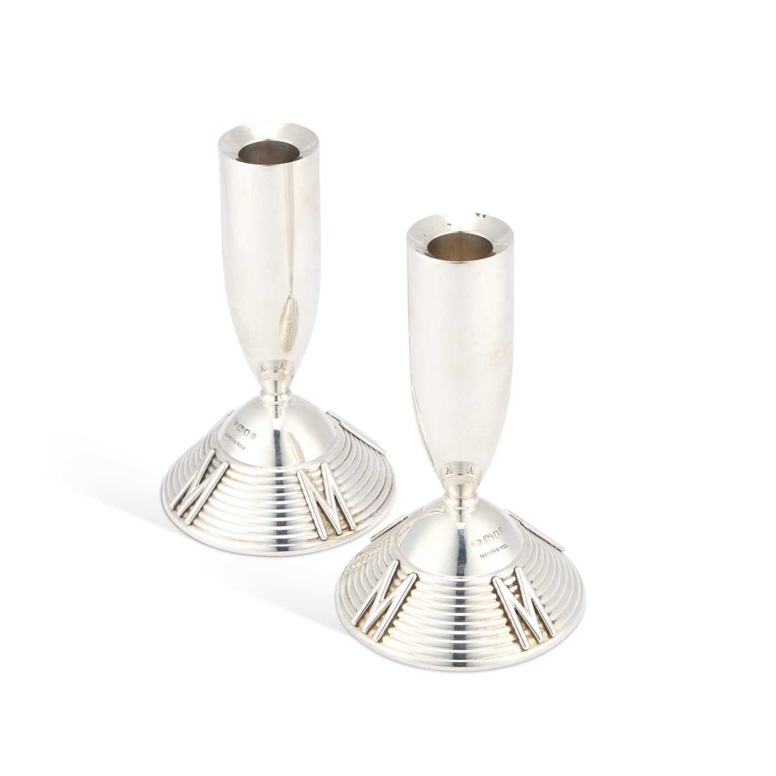 A PAIR OF ELIZABETH II SILVER ‘MILLENNIUM’ CANDLESTICKS: A PAIR OF ELIZABETH II SILVER ‘MILLENNIUM’ CANDLESTICKS by Mappin & Webb Ltd, London 1998, of rounded form upon a ribbed conical base with four applied letter Ms. (2) 15cm high, 12.