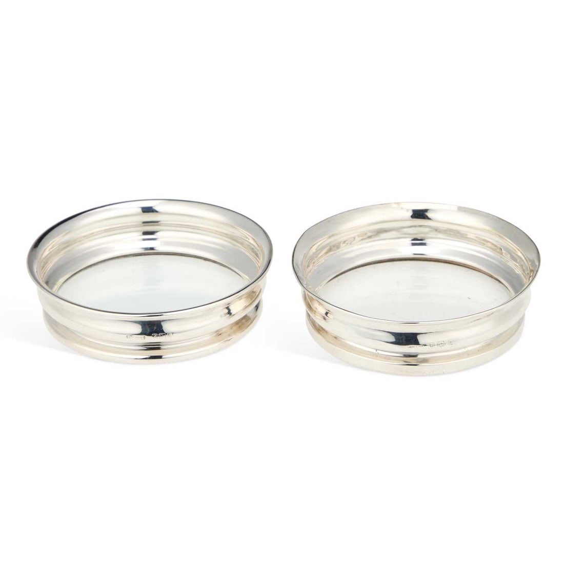 A NEAR PAIR OF GEORGE V SILVER-MOUNTED WINE COASTERS: A NEAR PAIR OF GEORGE V SILVER-MOUNTED WINE COASTERS maker's marks rubbed, Birmingham 1924 and 1927, each of circular form with a glass base. (2) 9cm diameter