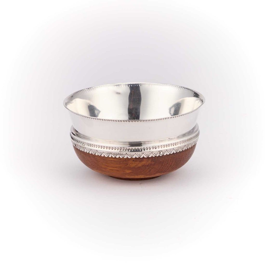 A 16TH CENTURY STYLE SILVER-MOUNTED OAK MAZER BOWL: A 16TH CENTURY STYLE SILVER-MOUNTED OAK MAZER BOWL by Thomas Bradbury & Sons Ltd, Sheffield 1943, the turned oak bowl on a short circular foot, the silver mount with a moulded lip, the lower borde