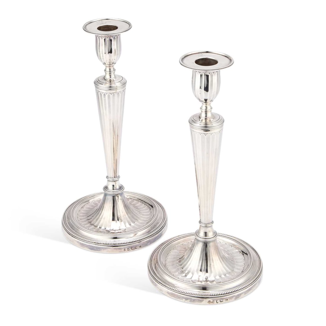 A PAIR OF GEORGE III NEOCLASSICAL SILVER CANDLESTICKS: A PAIR OF GEORGE III NEOCLASSICAL SILVER CANDLESTICKS by John Wakelin & William Taylor, London 1785, each of tapering Palmyran-fluted form, with beaded crested nozzles and a conforming beaded and