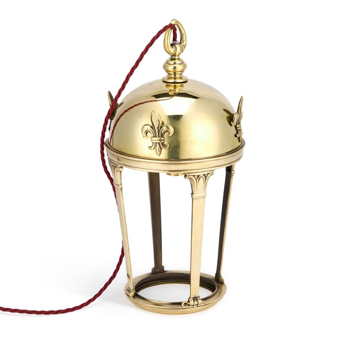 A BRASS DOME-TOP LANTERN: A BRASS DOME-TOP LANTERN the hemispherical cover applied with bold fleur-de-lis mounts and surmounted by a loop finial, raised on four tapering supports with stylised capitals united by a circular bas