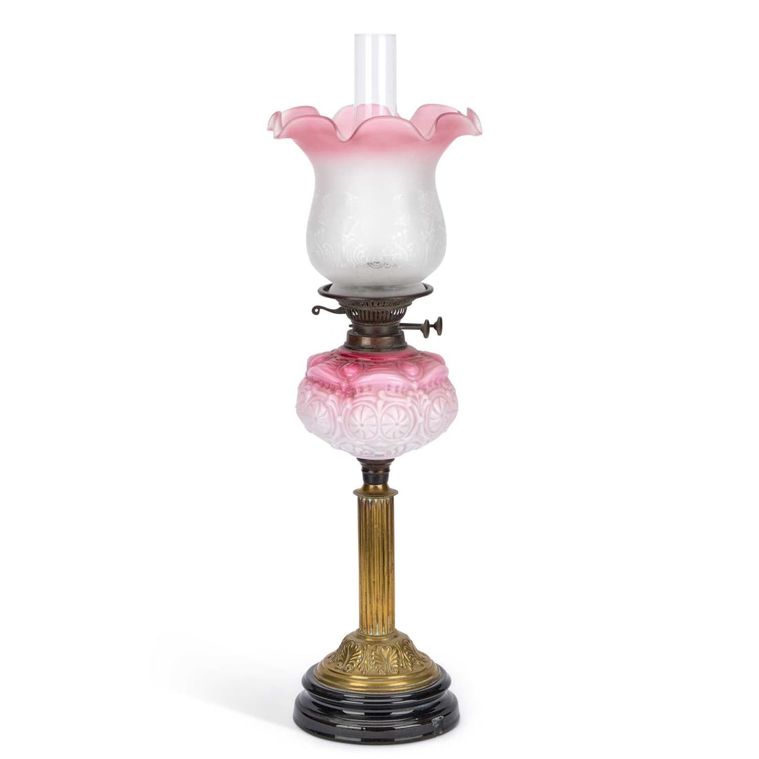 A VICTORIAN CRANBERRY AND OPAQUE GLASS OIL LAMP: A VICTORIAN CRANBERRY AND OPAQUE GLASS OIL LAMP the foliate-etched opaque and cranberry-tinted tulip shade over a moulded cranberry and white font of geometric design, raised on a reeded and cast bras