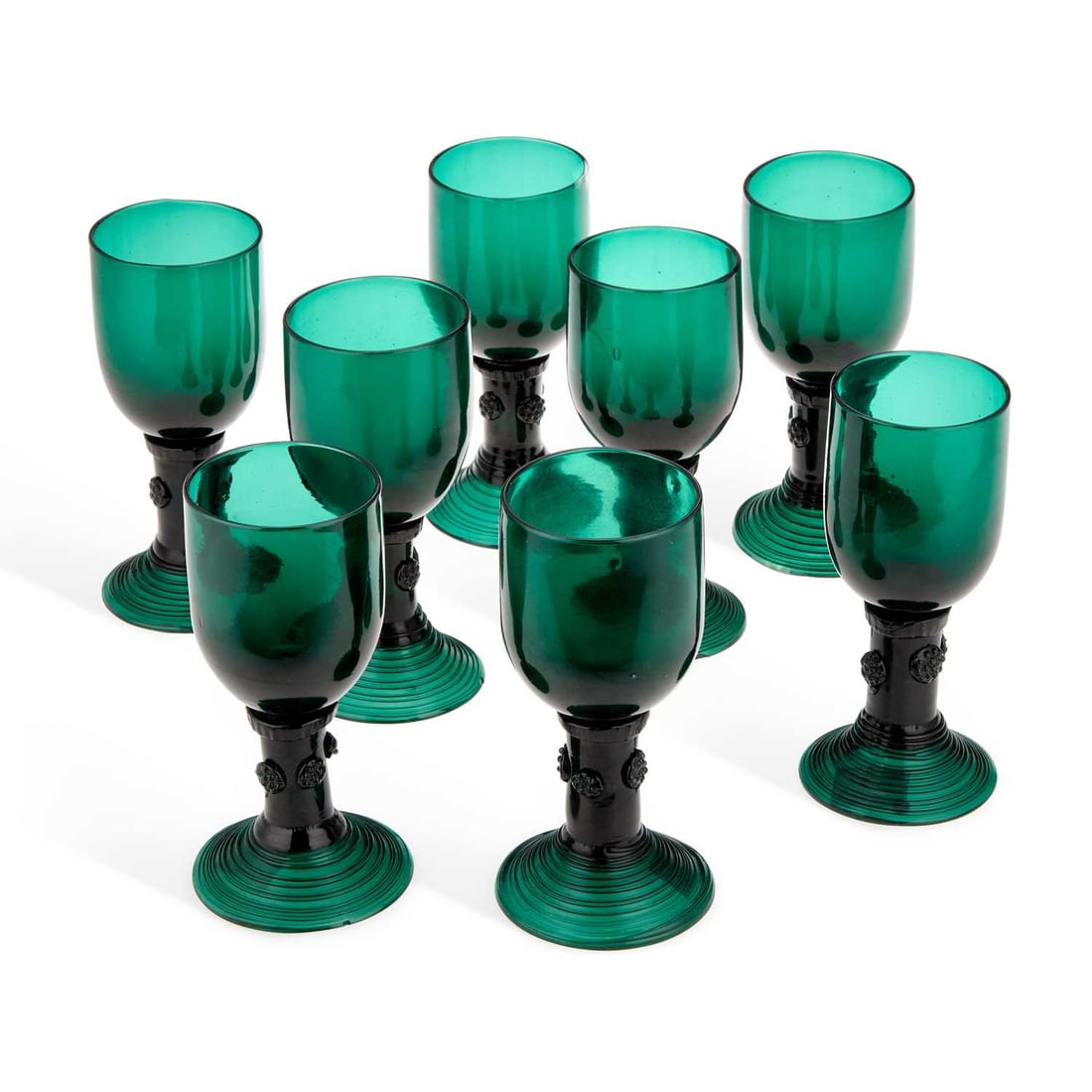 A SET OF EIGHT GREEN GLASS ROEMERS: A SET OF EIGHT GREEN GLASS ROEMERS each set upon a circular pedestal foot and embossed with prunts to the stem. (8) 14.8cm high