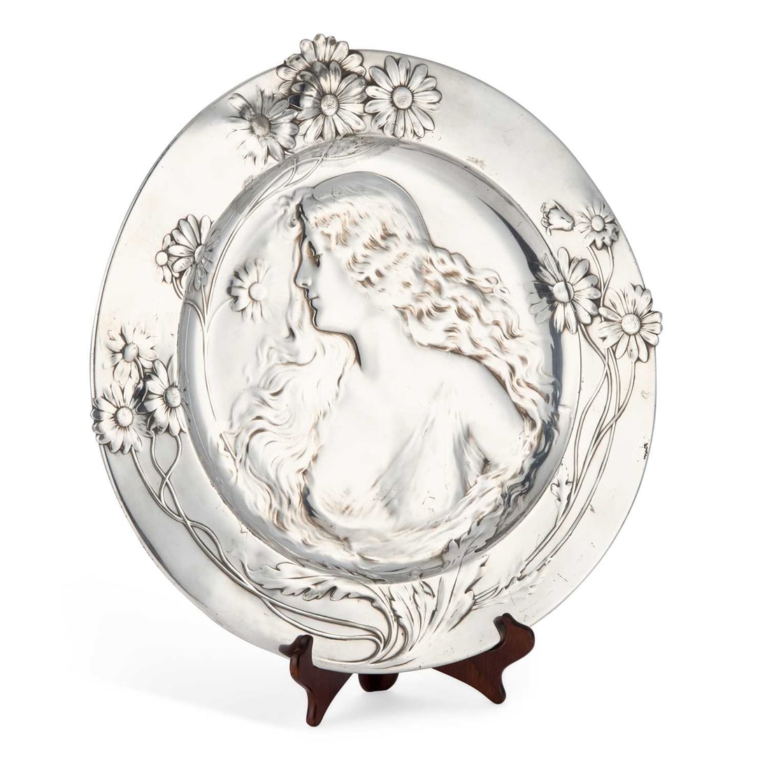 WMF (WÜRTTEMBERGISCHE METALLWARENFABRIK) A LARGE ART NOUVEAU PEWTER CHARGER: WMF (WÜRTTEMBERGISCHE METALLWARENFABRIK) A LARGE ART NOUVEAU PEWTER CHARGER centred with the bust of a maiden with flowing hair, the broad rim decorated with flowers, stamped marks to top reverse. Ap