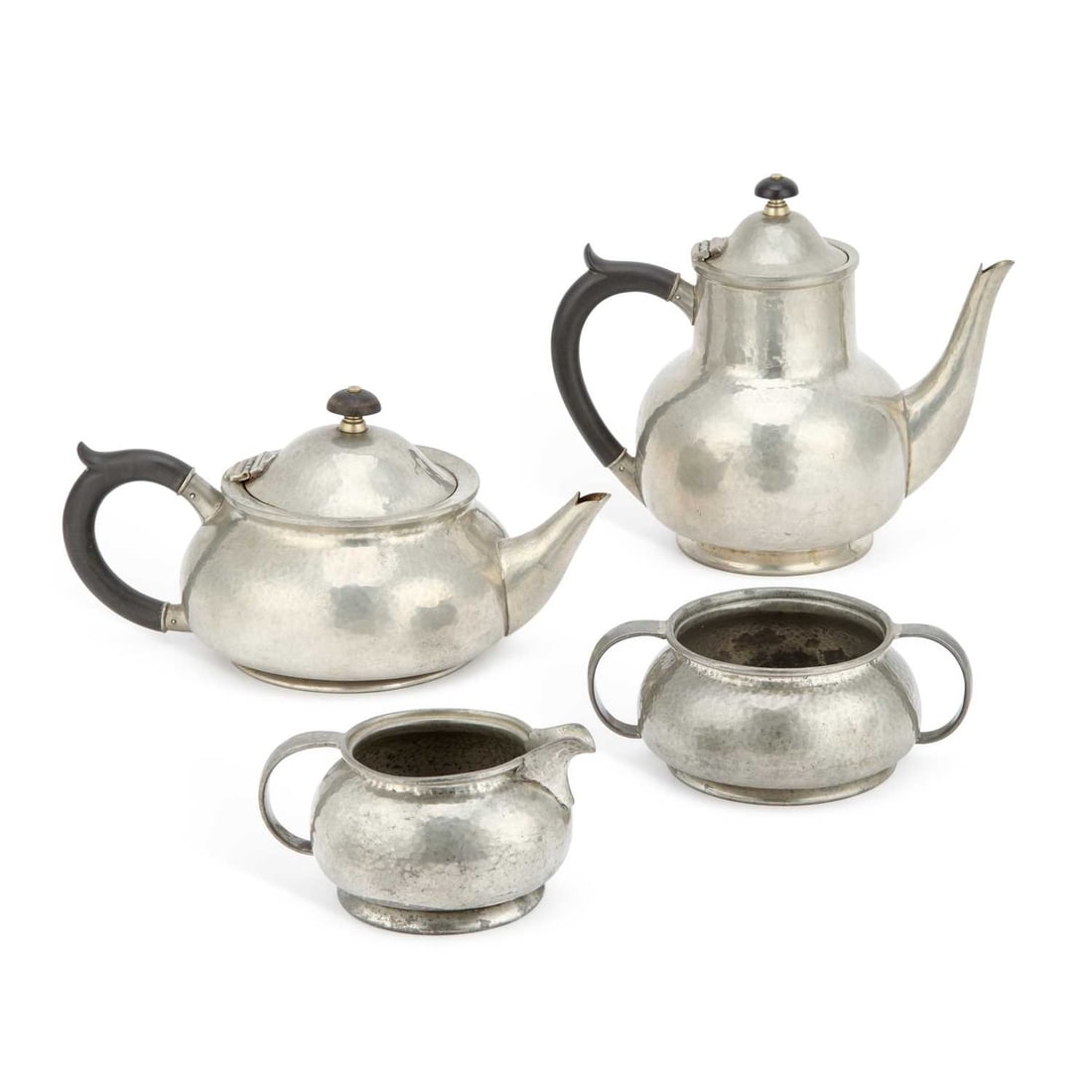 A LIBERTY & CO TUDRIC PEWTER FOUR-PIECE TEA SERVICE THE DESIGN ATTRIBUTED TO ARCHIBALD KNOX: A LIBERTY & CO TUDRIC PEWTER FOUR-PIECE TEA SERVICE THE DESIGN ATTRIBUTED TO ARCHIBALD KNOX (1864-1933) comprising teapot, coffee pot, milk jug and sugar bowl, each with hammered finish and stylised h