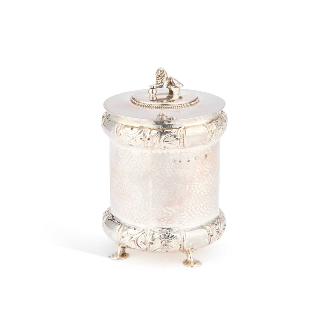 A. E. JONES, AN ARTS AND CRAFTS SILVER TEA CADDY: A. E. JONES, AN ARTS AND CRAFTS SILVER TEA CADDY by Albert Edward Jones, Birmingham 1913, retailed by Terry and Co., Manchester, of cylindrical form, raised on four pad feet, with stylised foliate bor
