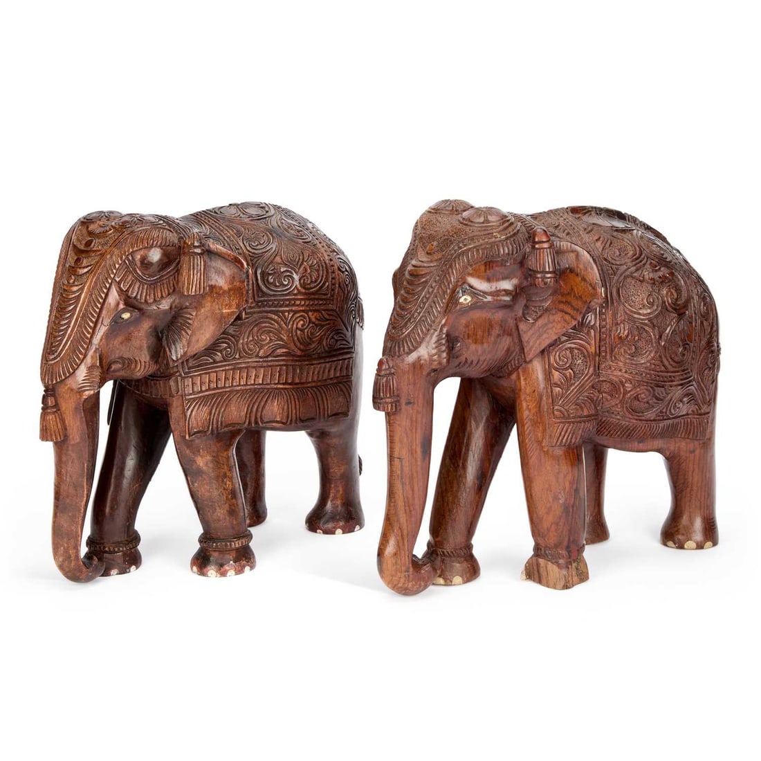A PAIR OF INDIAN CARVED WOOD ELEPHANTS CIRCA 1900: A PAIR OF INDIAN CARVED WOOD ELEPHANTS CIRCA 1900 the large caparisoned elephants wearing elaborately carved saddlecloths and headpieces, inlaid with bone eyes and toenails. (2) 35.5cm high, 41cm long