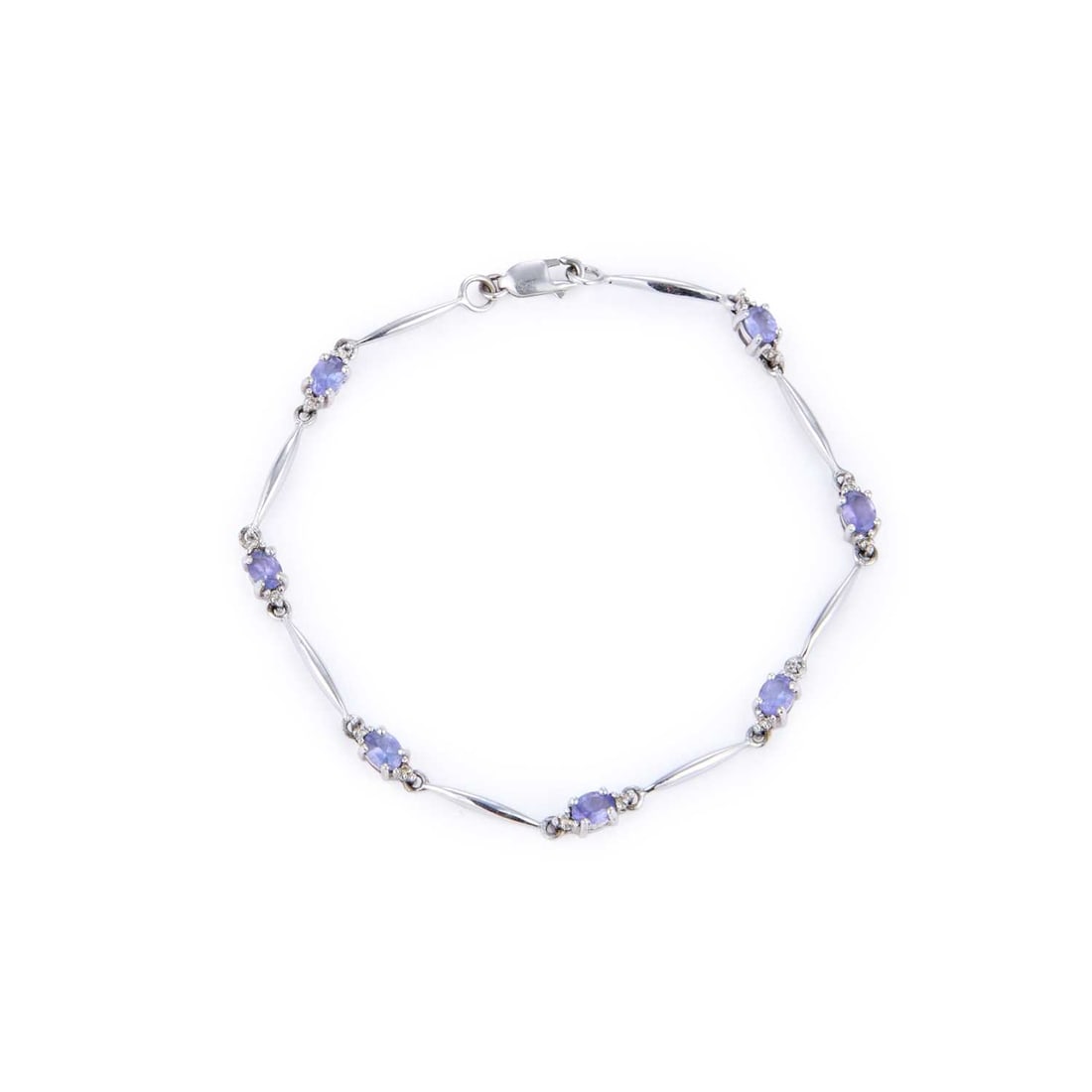 A TANZANITE BRACELET: A TANZANITE BRACELET oval-cut blue tanzanite flanked by round-cut white stone accents and spaced by tapering bar links, stamped '375'. 17.3cm long, 3.5 grams Good condition