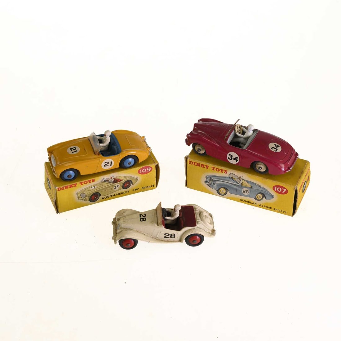 THREE DINKY DIECAST MODEL RACING CARS: THREE DINKY DIECAST MODEL RACING CARS comprising a red Sunbeam Alpine, no. 107, boxed; a yellow Austin Healey, no. 109, boxed; a white M.G. Midget, no. 108. (3)