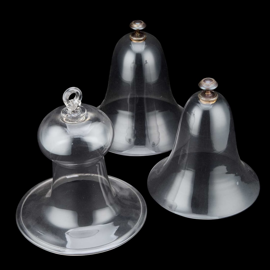 A PAIR OF BELL-SHAPED GLASS CLOCHES: A PAIR OF BELL-SHAPED GLASS CLOCHES each with an unmarked white metal handle; together with a 19th Century bell-shaped glass cloche with a folded rim. (3) Tallest 28cm