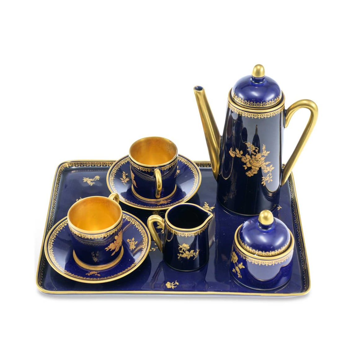 A LIMOGES PORCELAIN CABARET SET: A LIMOGES PORCELAIN CABARET SET decorated with gilt sprays of flowers on a cobalt blue ground, comprising a coffee pot, milk jug, sucrier, two coffee cans and covers and a tray, printed factory
