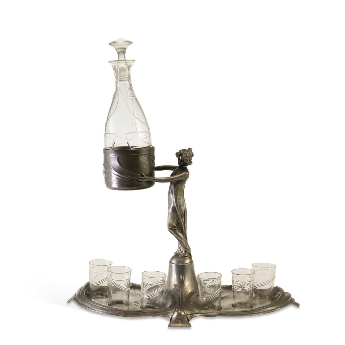 WMF (WÜRTTEMBERGISCHE METALLWARENFABRIK), AN ART NOUVEAU PEWTER LIQUEUR SET CIRCA 1900: WMF (WÜRTTEMBERGISCHE METALLWARENFABRIK), AN ART NOUVEAU PEWTER LIQUEUR SET CIRCA 1900 modelled as a young girl in a long gown, holding the glass decanter in a large vessel, above the foliate form ba