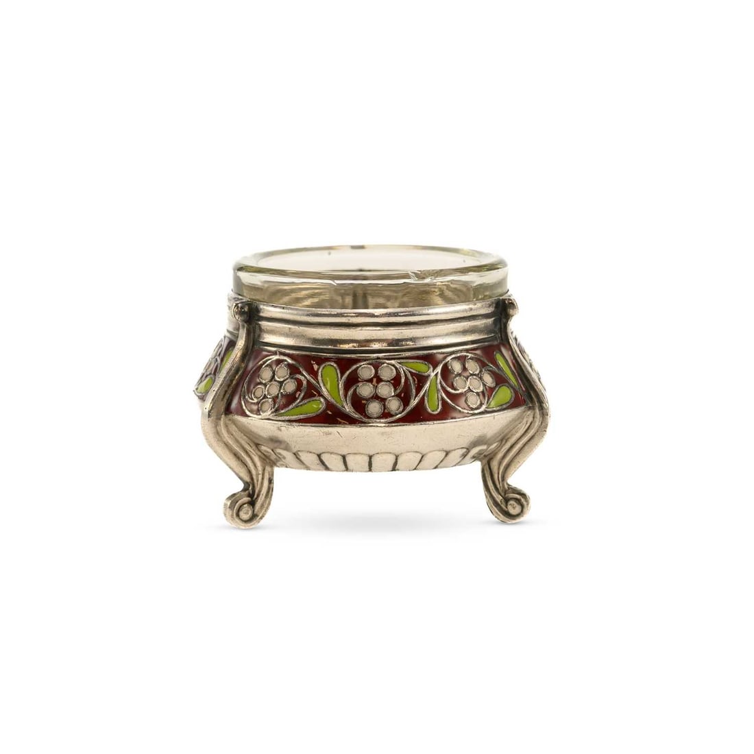 A POSSIBLY RUSSIAN SILVER AND ENAMEL SALT: A POSSIBLY RUSSIAN SILVER AND ENAMEL SALT of circular form, decorated with white flowers and green leaves against a translucent red enamel ground, raised on three scroll feet and fitted with a clear g