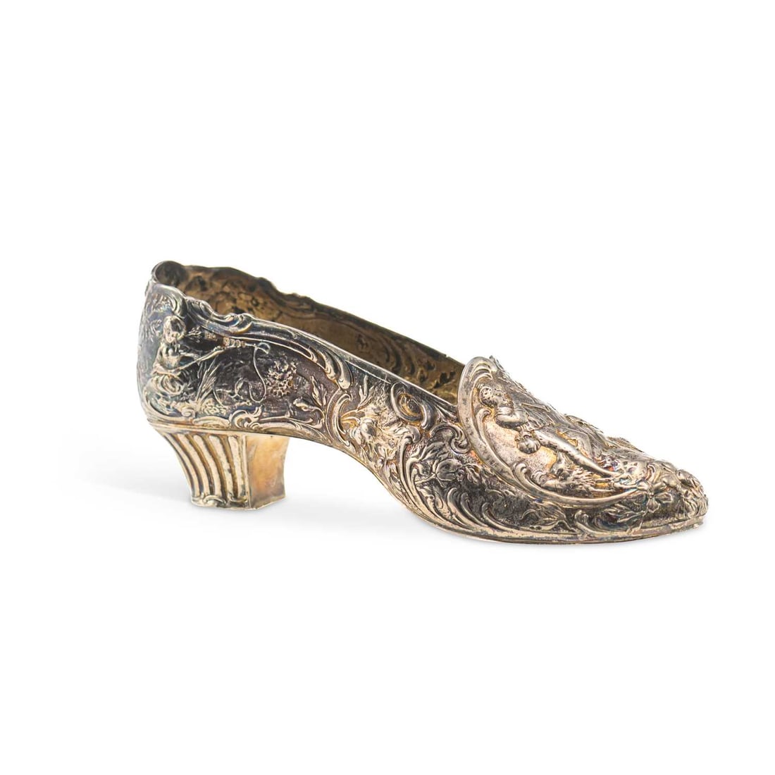 A GERMAN SILVER MODEL OF A SHOE: A GERMAN SILVER MODEL OF A SHOE Hanau, import marks for Berthold Muller, London 1895, chased Rococo decoration of a piper and a shepherdess within a landscape. 18.5cm long, 6.3 troy ounces