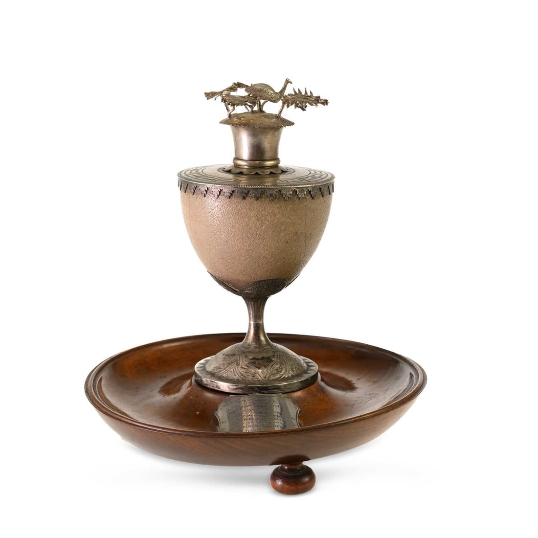 A 19TH CENTURY AUSTRALIAN SILVER-MOUNTED EMU EGG PRESENTATION CUP: A 19TH CENTURY AUSTRALIAN SILVER-MOUNTED EMU EGG PRESENTATION CUP maker J.T.S., the hinged cover surmounted by an emu amid fern fronds, the mounts engraved with geometric and foliate decoration, raise