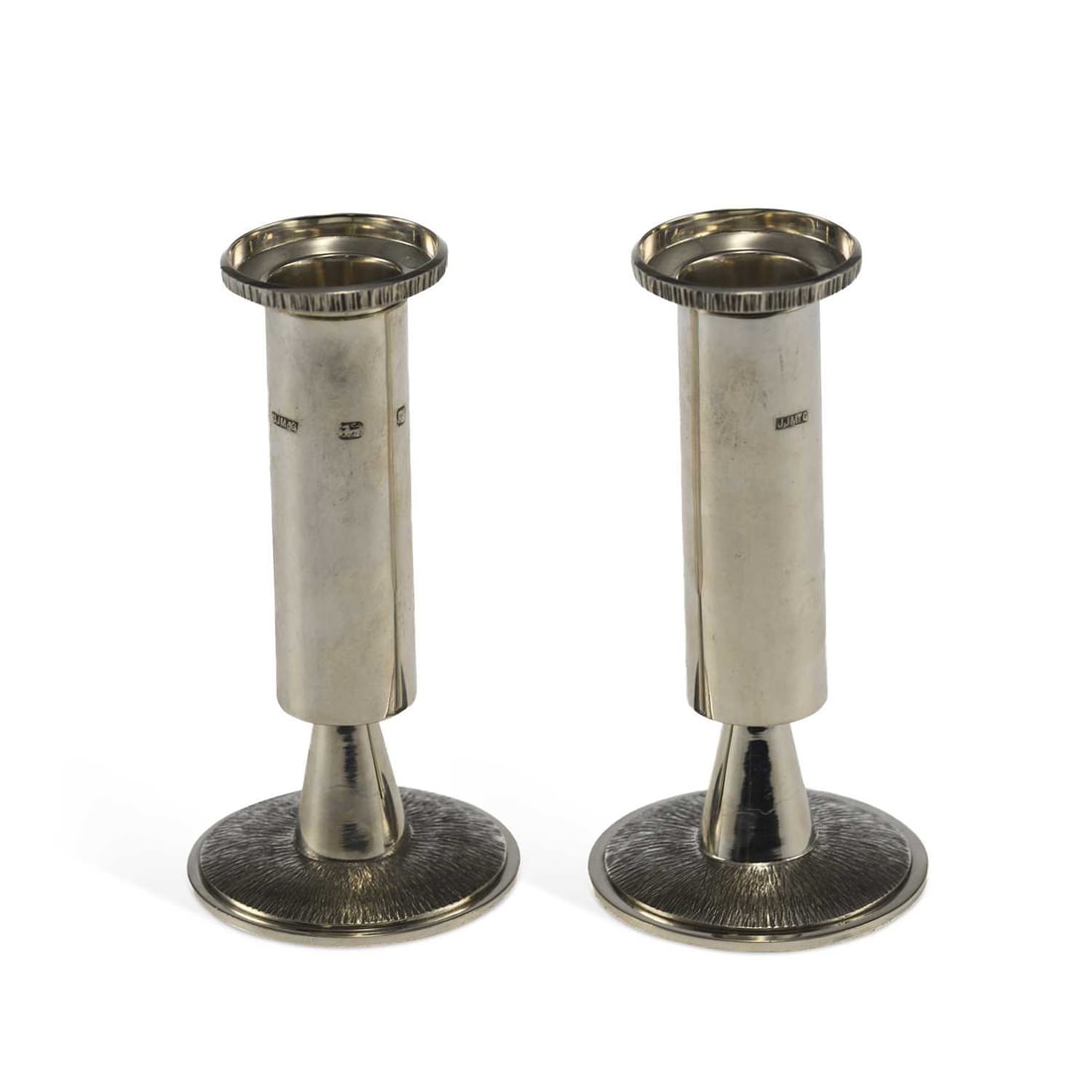 A PAIR OF ELIZABETH II MODERNIST SILVER CANDLESTICKS: A PAIR OF ELIZABETH II MODERNIST SILVER CANDLESTICKS by John James McGreal, London 1977, Jubilee mark, of circular form, with textured foot and detachable sconces. (2) 13.7cm high, 11.4 troy ounces gr