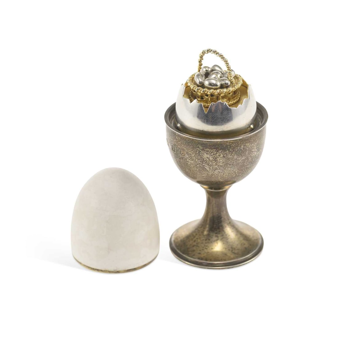 AN ELIZABETH II PARCEL-GILT SILVER LIMITED EDITION SURPRISE EGG: AN ELIZABETH II PARCEL-GILT SILVER LIMITED EDITION SURPRISE EGG by Anthony Gordon Elson, London 1979, numbered 11/200, the detachable enamelled shell cover opening to reveal a rise and fall basket of 