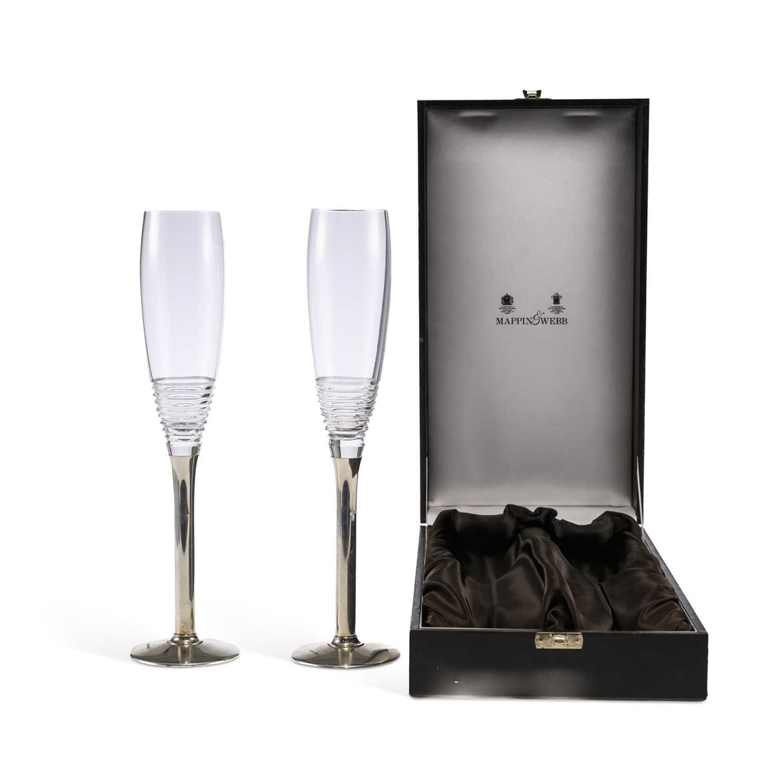 A PAIR OF ELIZABETH II SILVER-MOUNTED CHAMPAGNE FLUTES: A PAIR OF ELIZABETH II SILVER-MOUNTED CHAMPAGNE FLUTES by Mappin & Webb Ltd, London 2001, the cut-glass bowls with ribbed decoration, on silver stems of plain form with circular feet, within a fit