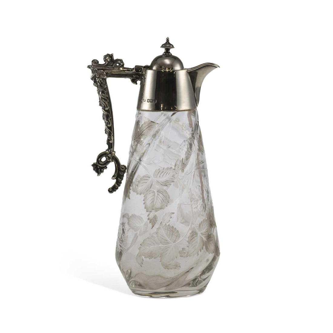 AN EDWARDIAN SILVER-MOUNTED CUT-GLASS CLARET JUG: AN EDWARDIAN SILVER-MOUNTED CUT-GLASS CLARET JUG by William Mammat & Son, Sheffield 1905, with a scroll motif handle, the wrythen body engraved with leaf and berry motif. 27cm high