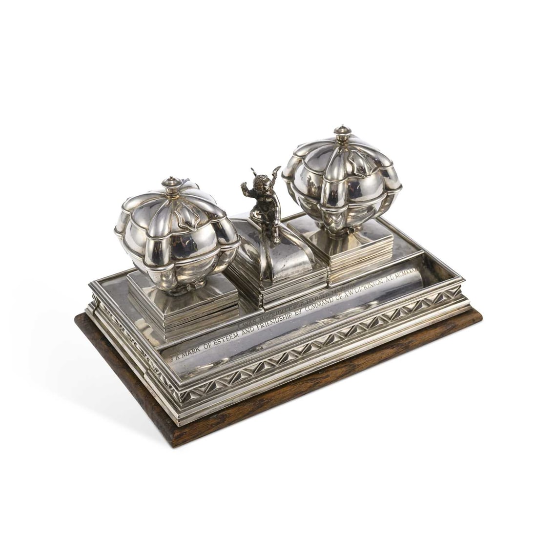 OMAR RAMSDEN: A GEORGE V SILVER INKSTAND: OMAR RAMSDEN: A GEORGE V SILVER INKSTAND by Omar Ramsden, London 1931, of rectangular form, centrally mounted with a covered card tray, the finial in the form of a winged figure of cupid, between a pa