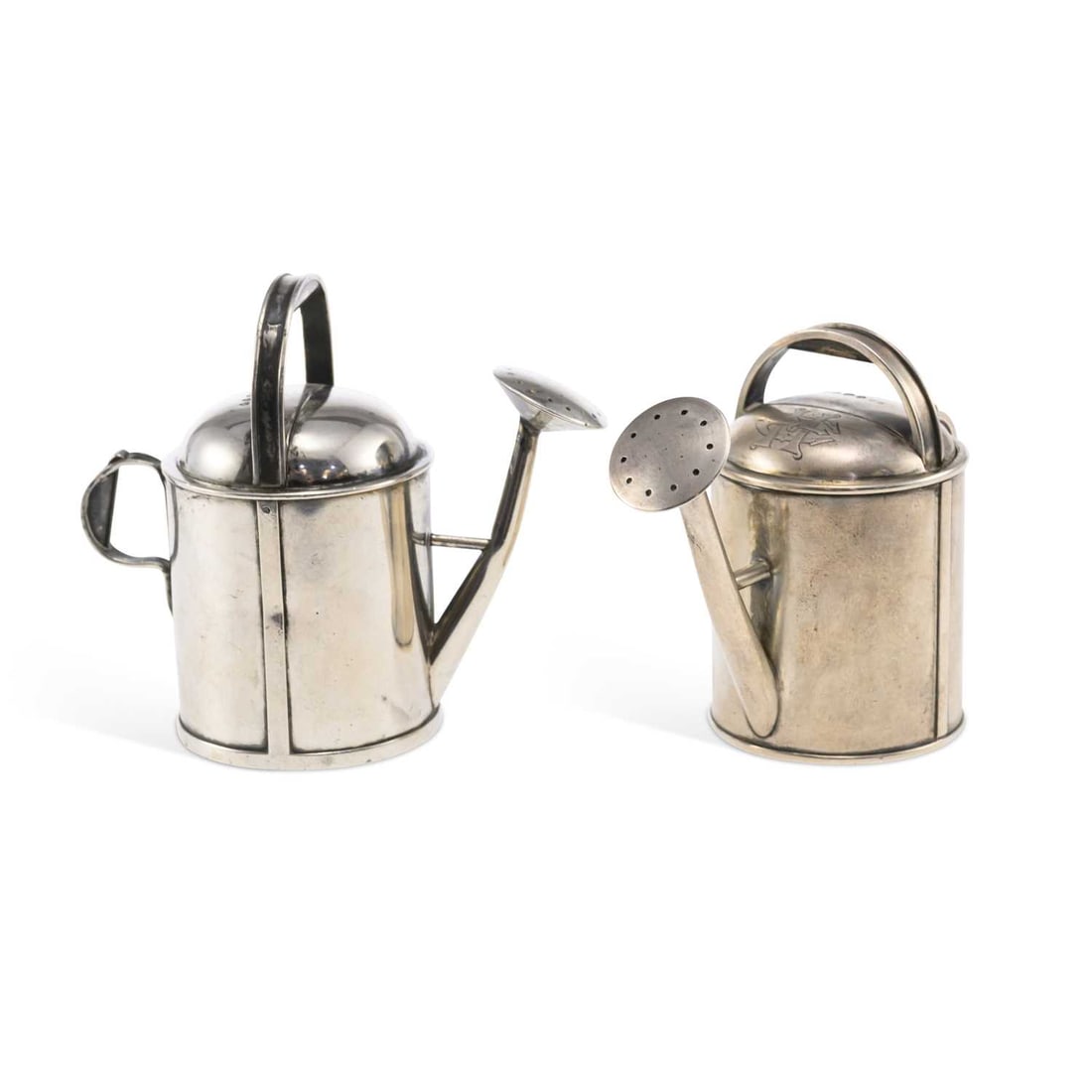 A MATCHED PAIR OF VICTORIAN NOVELTY PEPPER POTS: A MATCHED PAIR OF VICTORIAN NOVELTY PEPPER POTS one maker's mark worn, the other by Thomas Johnson II, London, 1879 and 1886, each in the form of a watering can with carrying handle and pierced spout,