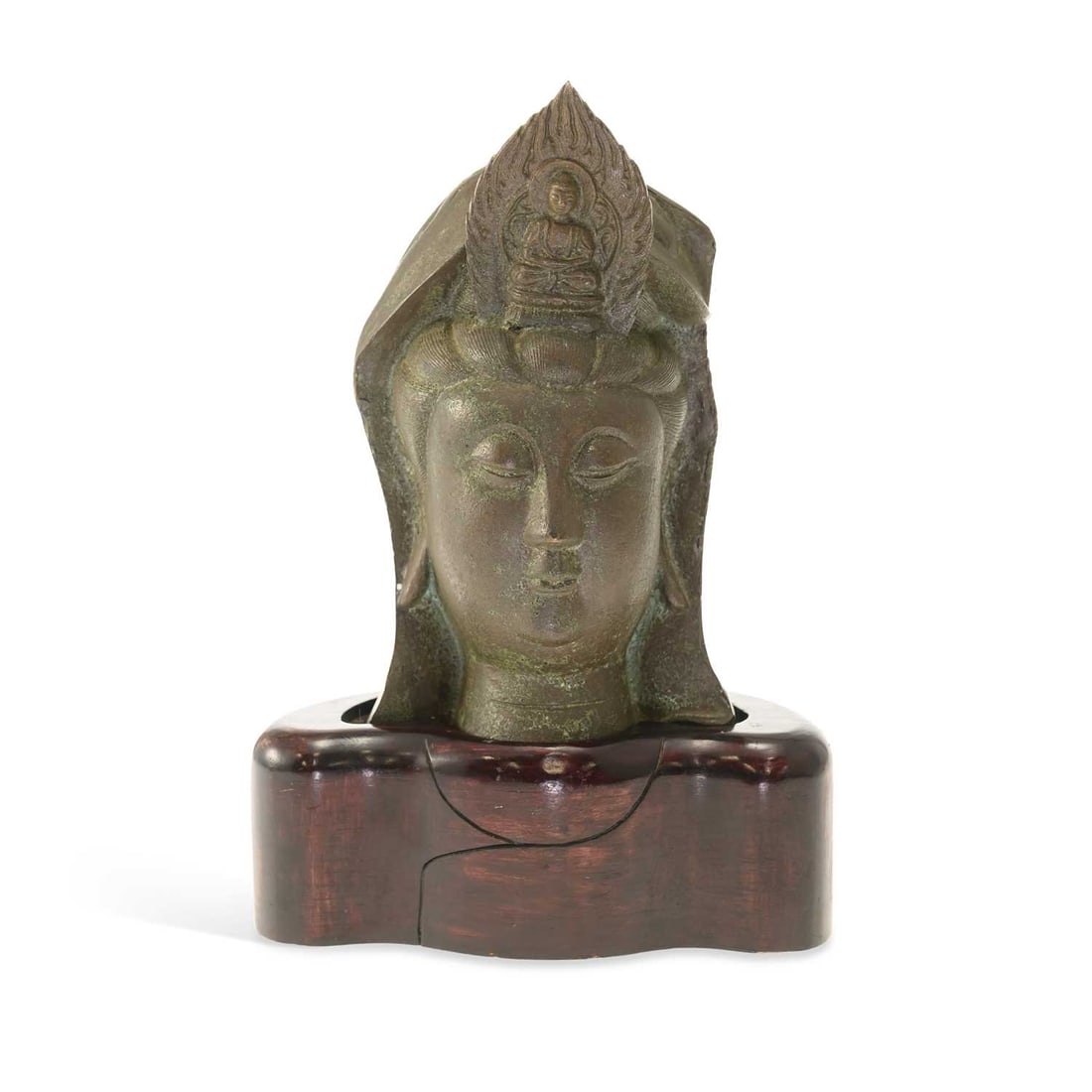 A CHINESE PATINATED BRONZE HEAD OF GUANYIN: A CHINESE PATINATED BRONZE HEAD OF GUANYIN the serene face with downcast eyes beneath a high headdress centred by a seated figure of Amitabha Buddha within a flame-shaped mandorla, mounted on a carved