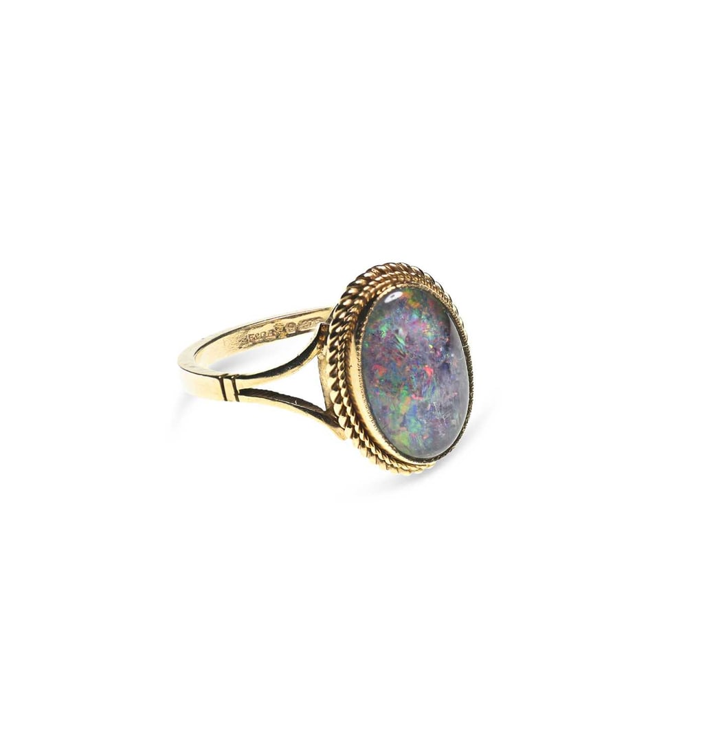 A 9 CARAT GOLD BLACK OPAL RING: A 9 CARAT GOLD BLACK OPAL RING an oval black opal within a rope frame, to forked shoulders, hallmarked Birmingham 1993. Ring size N, 2.9 grams Good condition