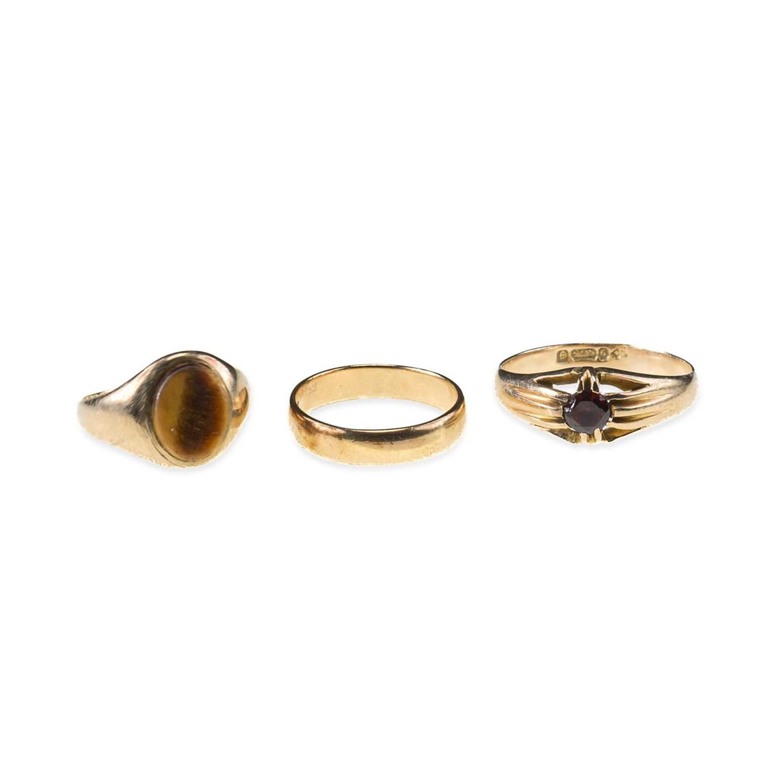 THREE 9 CARAT GOLD RINGS: THREE 9 CARAT GOLD RINGS comprising a band ring, hallmarked; a garnet ring, hallmarked; and a tigers eye signet ring, hallmarked. (3) Ring size K and Q, 8.4 grams gross Good condition