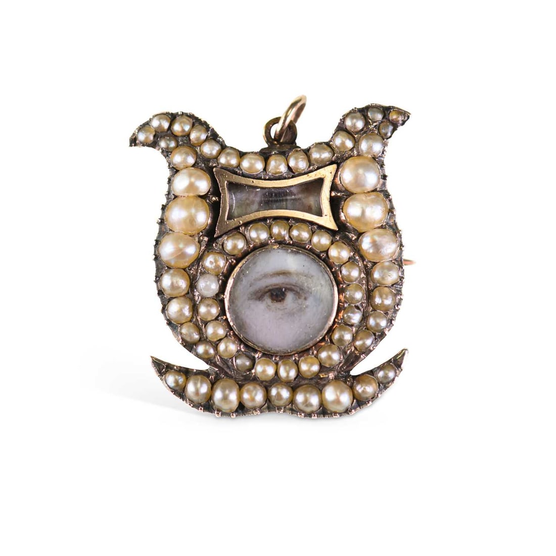 § AN EARLY 19TH CENTURY GOLD, SEED PEARL AND LOVER’S EYE MEMORIAL BROOCH/ PENDANT: § AN EARLY 19TH CENTURY GOLD, SEED PEARL AND LOVER’S EYE MEMORIAL BROOCH/ PENDANT of shield form, centred by a glazed eye miniature, within pearl borders, the hinged reverse with an engraved