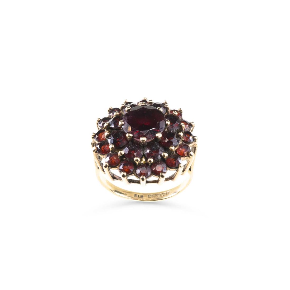 A 9 CARAT GOLD GARNET CLUSTER RING: A 9 CARAT GOLD GARNET CLUSTER RING a round-cut garnet within a border of smaller garnets, Birmingham 1972. Ring size I, 6.1 grams Good condition.